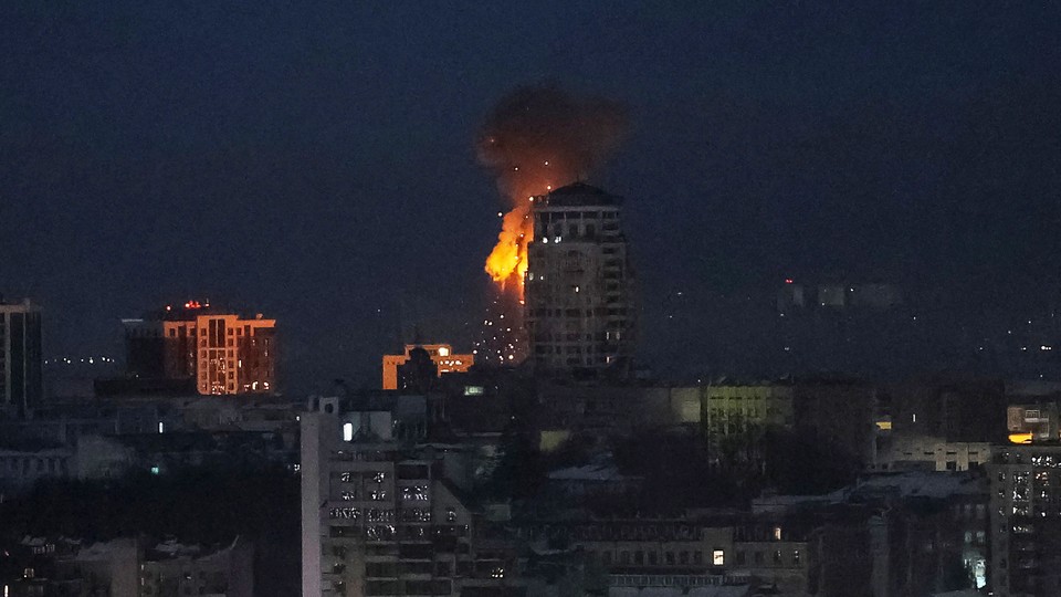 Flames are visible in a night sky behind a high-rise in Kyiv.