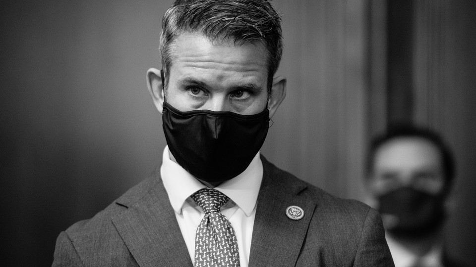 Representative Adam Kinzinger wears a black mask and suit