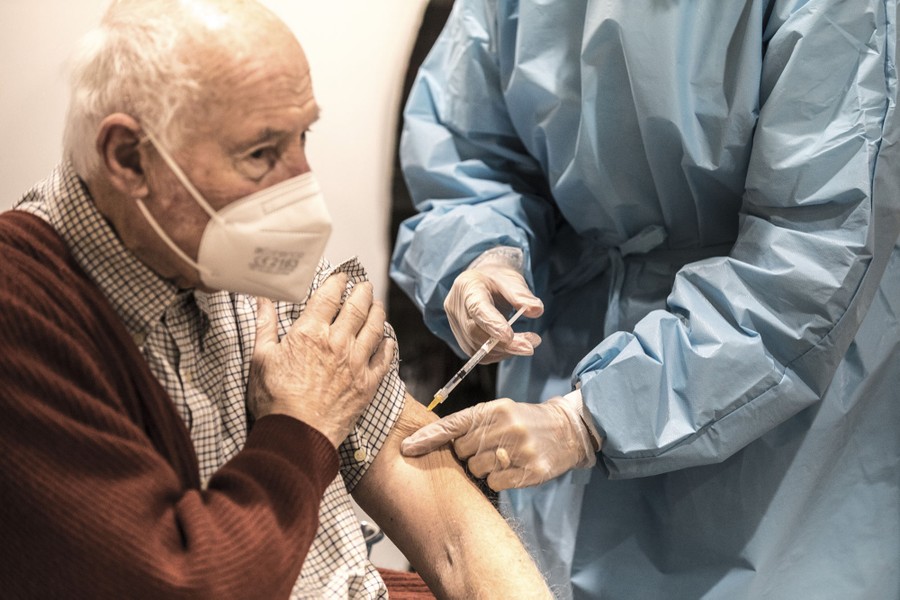A nurse gives a man a shot in his arm.