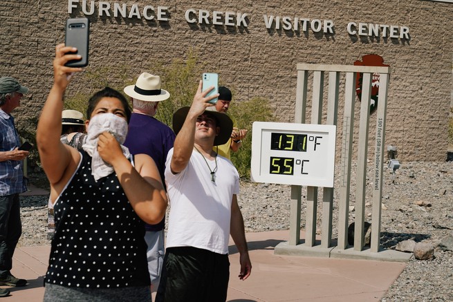 People take selfies at the Furnace Creek Visitor Center thermometer in Death Valley, California, which shows 131 degrees Fahrenheit and 55 degrees Celsius.