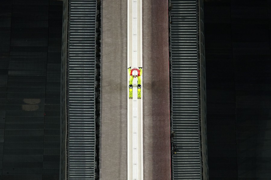 A ski jumper is seen descending a hill.
