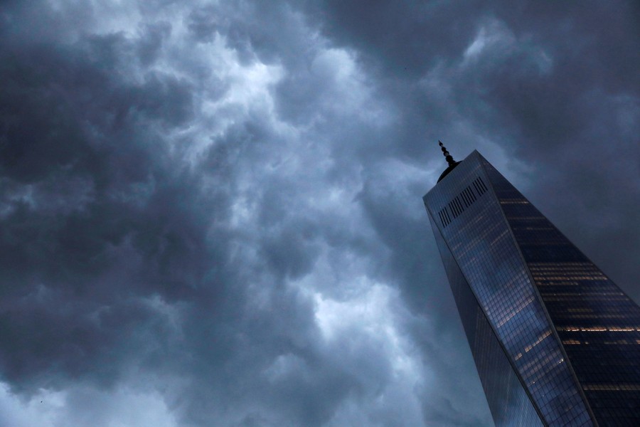 Storm clouds pass above a tall skyscraper.