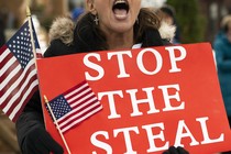 A woman yells while holding a "STOP THE STEAL" sign