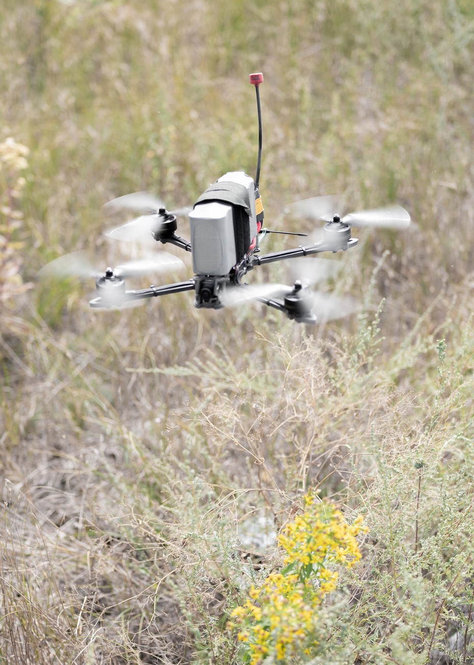 A small surveillance drone hovering over a field.