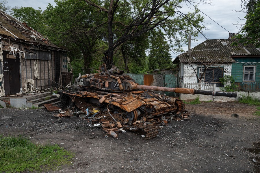 The wreckage of a destroyed tank sits near houses.