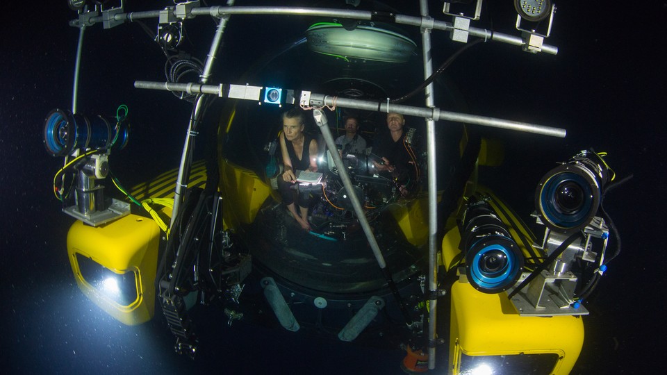 People in a submersible with lots of lights and cameras