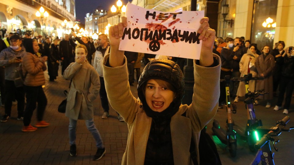 A protester holds a hand-written sign that reads "No 'burialization'" in Russian.