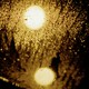 A yellow light shines through a glass with raindrops on it.