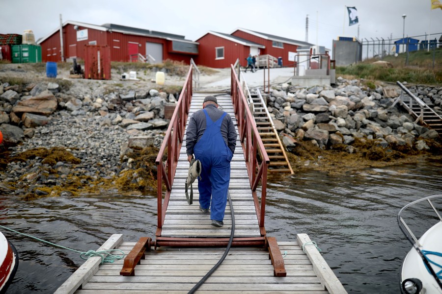 A man wearing overalls walks up a ramp from a floating dock.