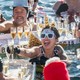 A group of swimmers in party hats drink champagne together.