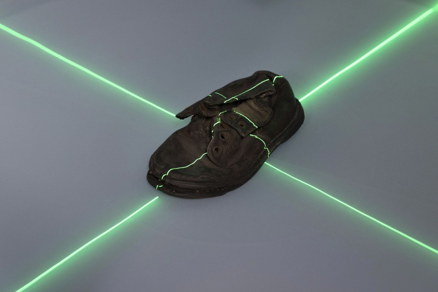 A small, decades-old child's shoe is scanned by green lasers.
