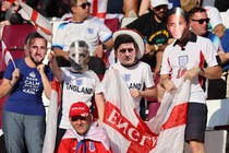 England fans wear masks of players and hold up an English flag