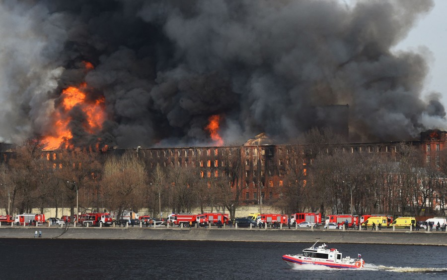 A massive building burns along a riverside.