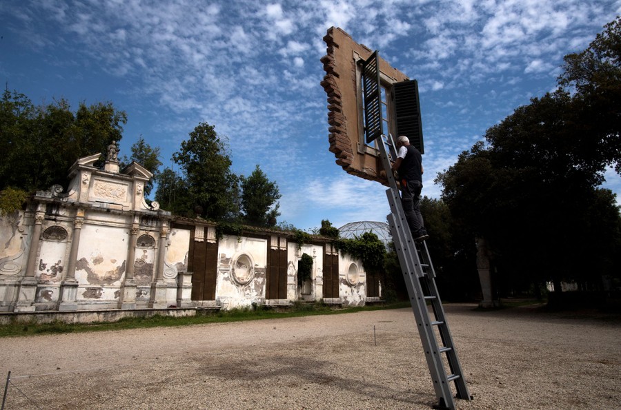 A person stands atop a ladder leaning on a windowsill that appears to float in the air.