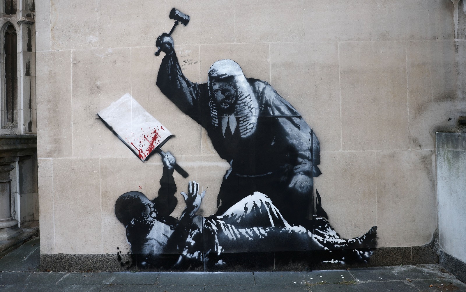 A mural painted on a wall, apparently depicting a British judge swinging a gavel toward an injured protester.