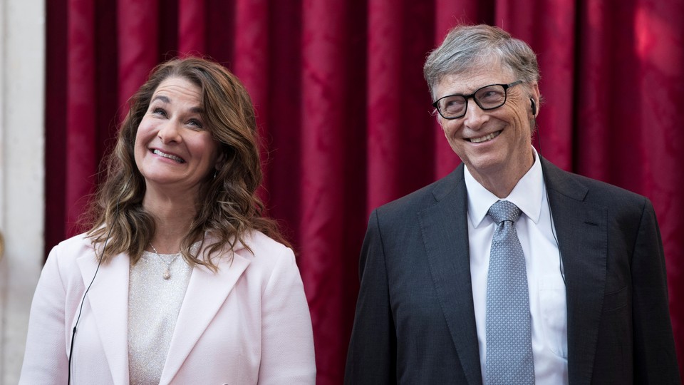Bill and Melinda Gates smile broadly in front of a red curtain.