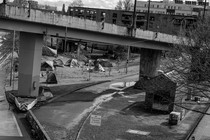 A black and white scene of tents underneath an overpass