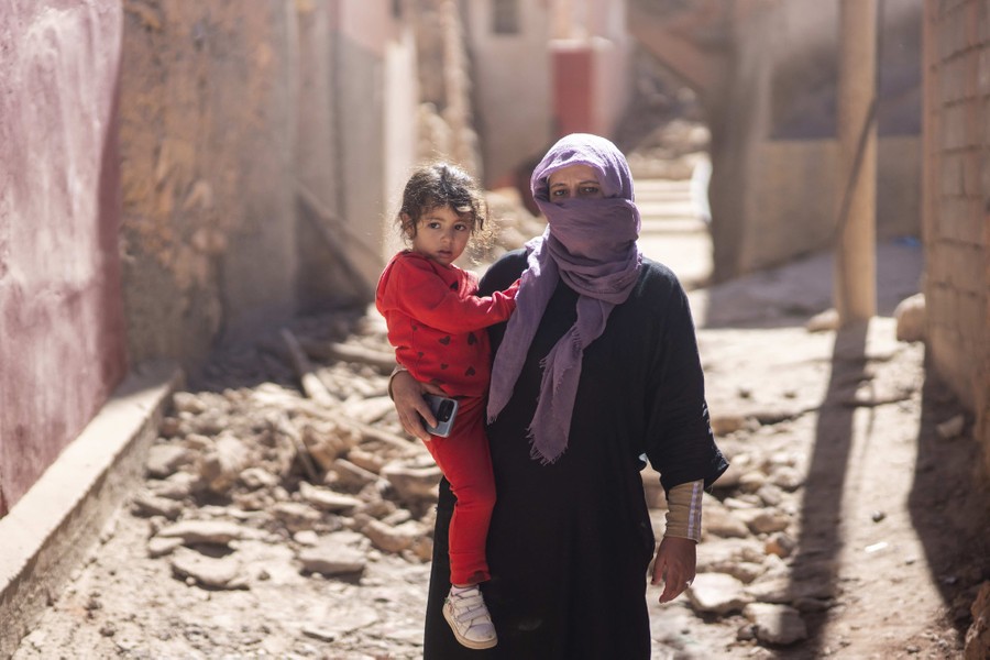 A woman and her daughter stand outside their quake-damaged home.