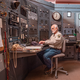 photo of two uniformed men sitting in control center with huge analog machinery bank in background