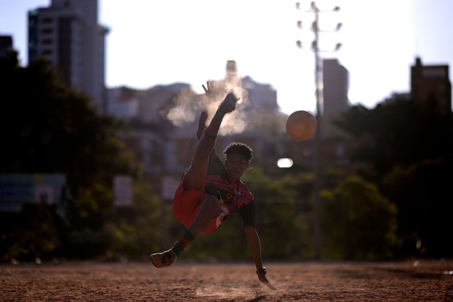 A soccer player practices, falling while kicking a ball.