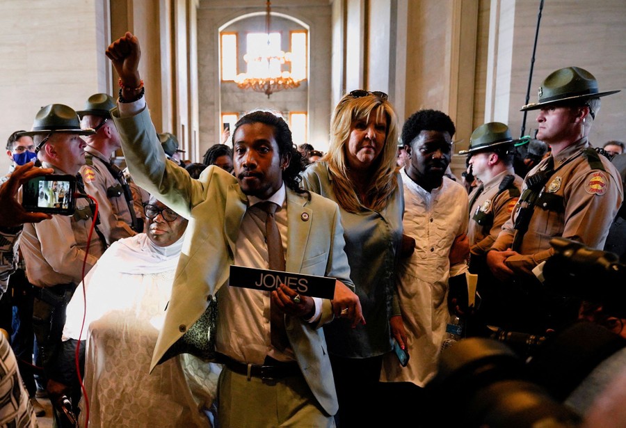 A man raises his fist while walking with others past state troopers inside the Tennessee State Capitol.
