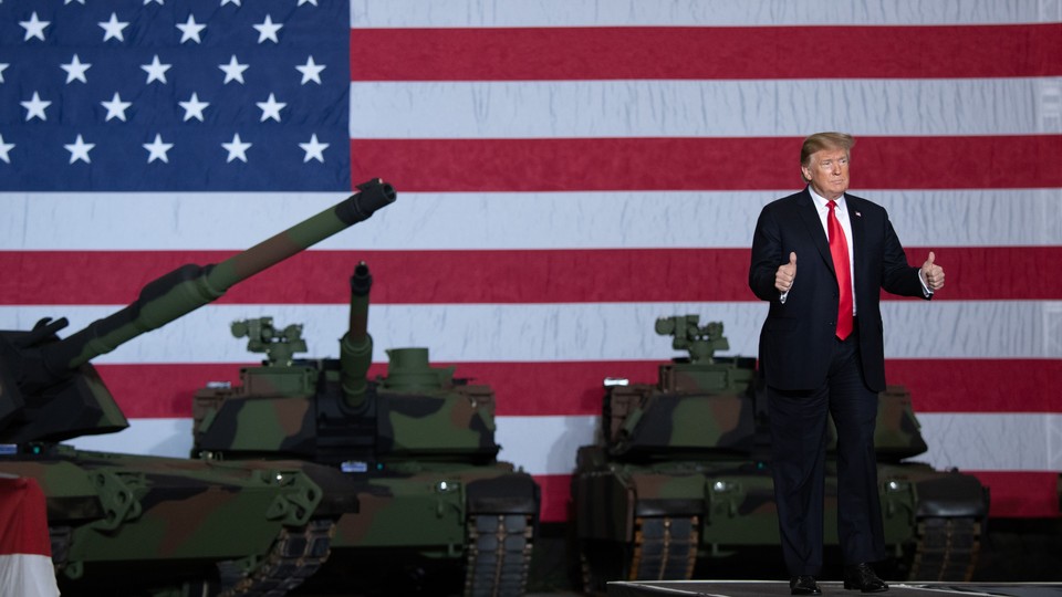 Donald Trump standing in front of tanks and an American-flag backdrop