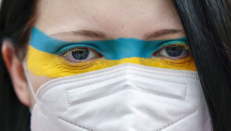 A protester is seen in close-up, two stripes of color painted across their face.