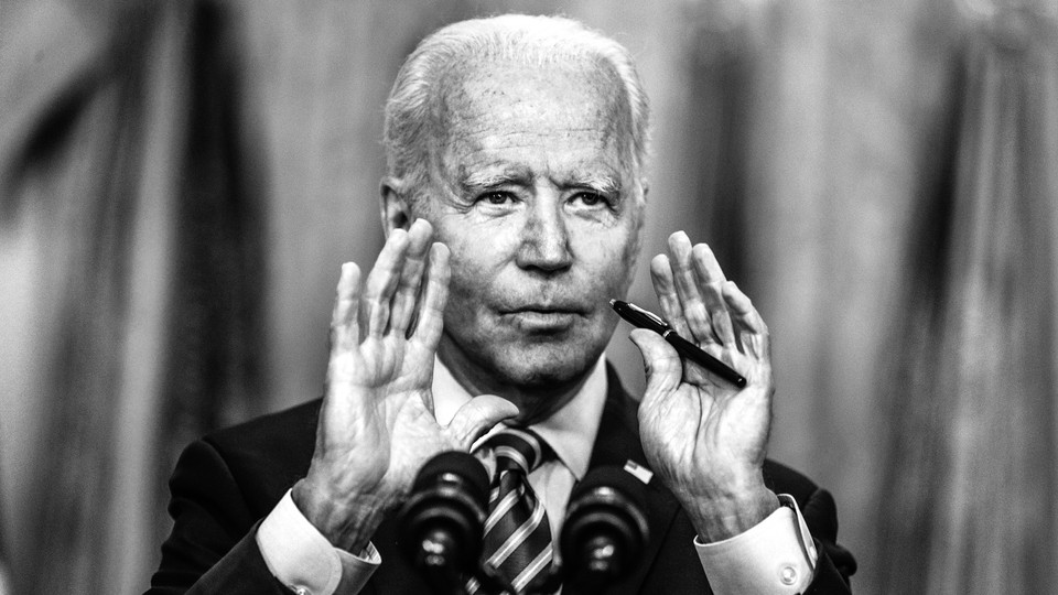 President Joe Biden speaks into a microphone with his hands held up to frame the lower half of his face.