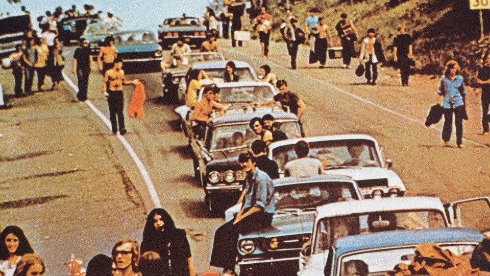 Concertgoers at Woodstock pile outside in cars.