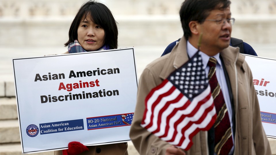 Two Asians hold signs opposing racial discrimination in college admissions outside the Supreme Court
