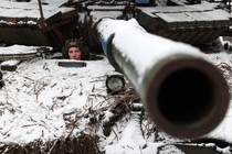 A Ukrainian soldier looks out from a tank, and its barrel points at the viewer