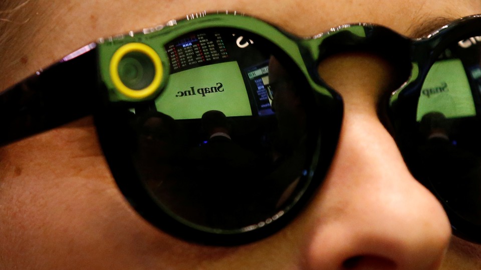 A woman wears Snapchat Spectacles on the floor of the New York Stock Exchange while waiting for Snap Inc. to list their IPO