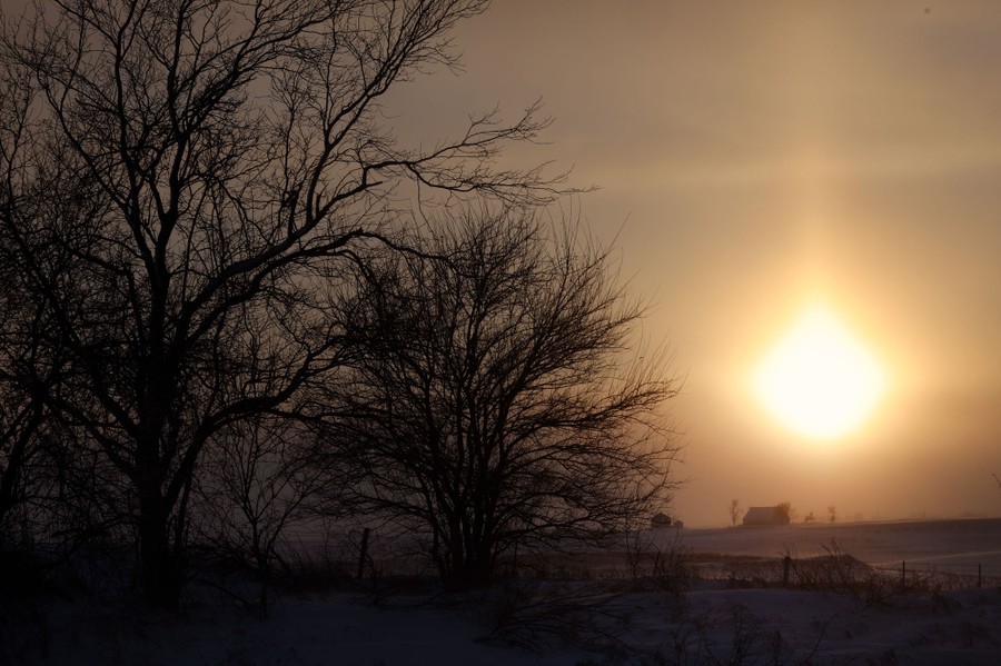 The sun sets over a snow-covered field in Iowa.