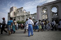 A procession walks past the ruins of the Notre-Dame de l'Assomption cathedral, destroyed in the 2010 earthquake.