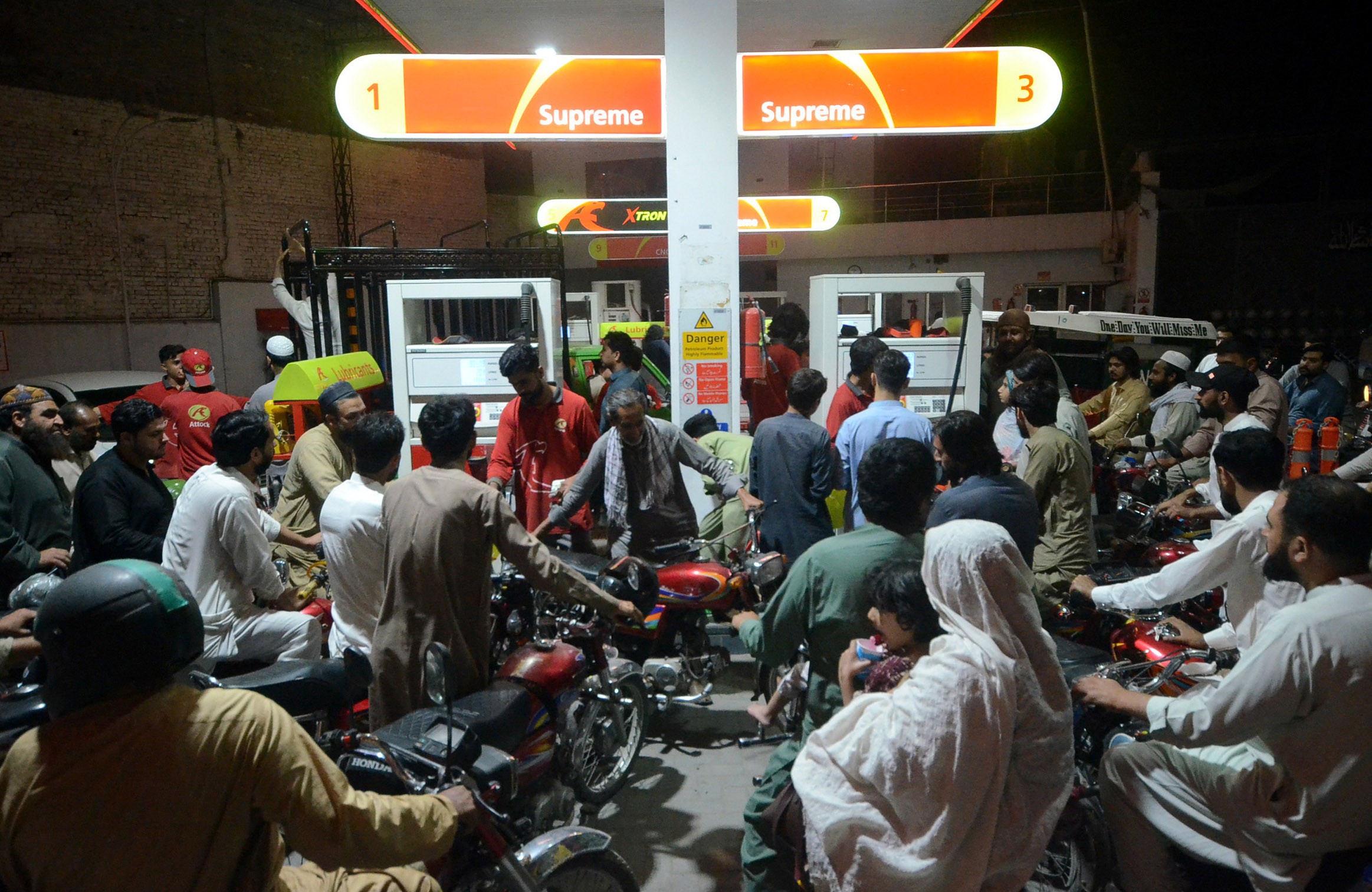 Many vehicles line up in a disorderly fashion for fuel at a gas station.