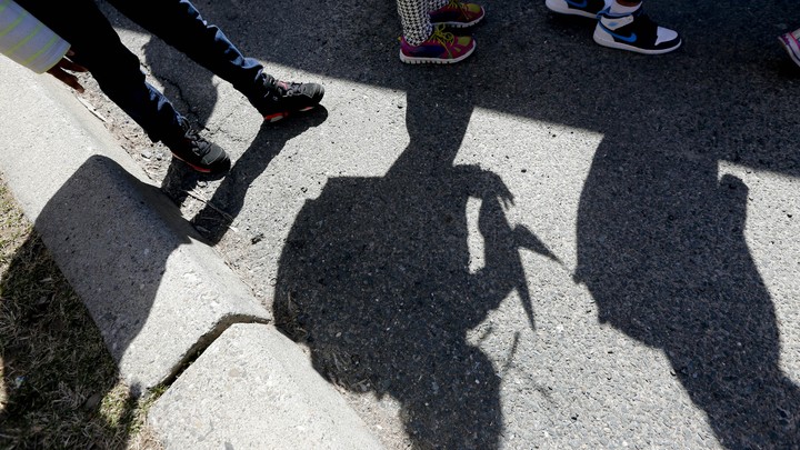 Shadows of students and their sneakers waiting for a school bus