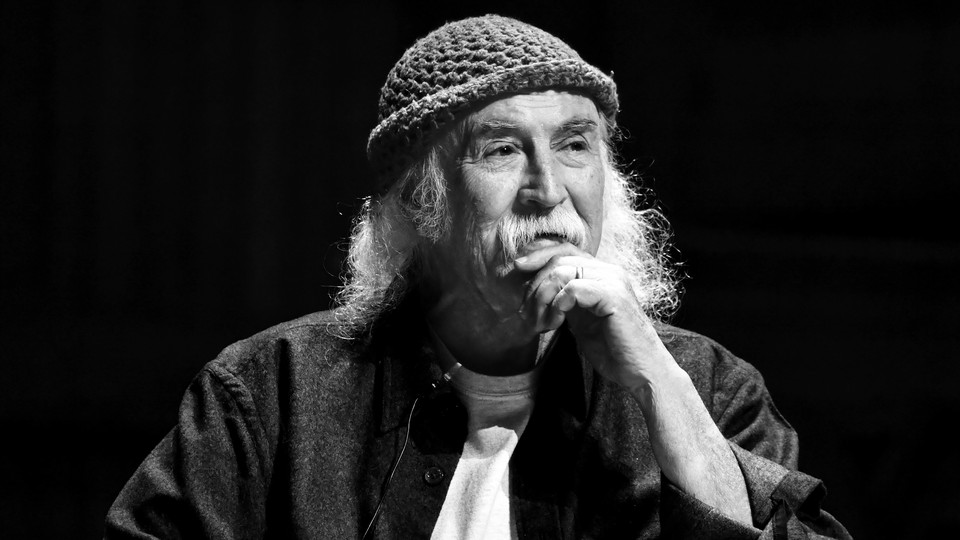 a black and white image of David Crosby in a knit cap with his hand to his chin