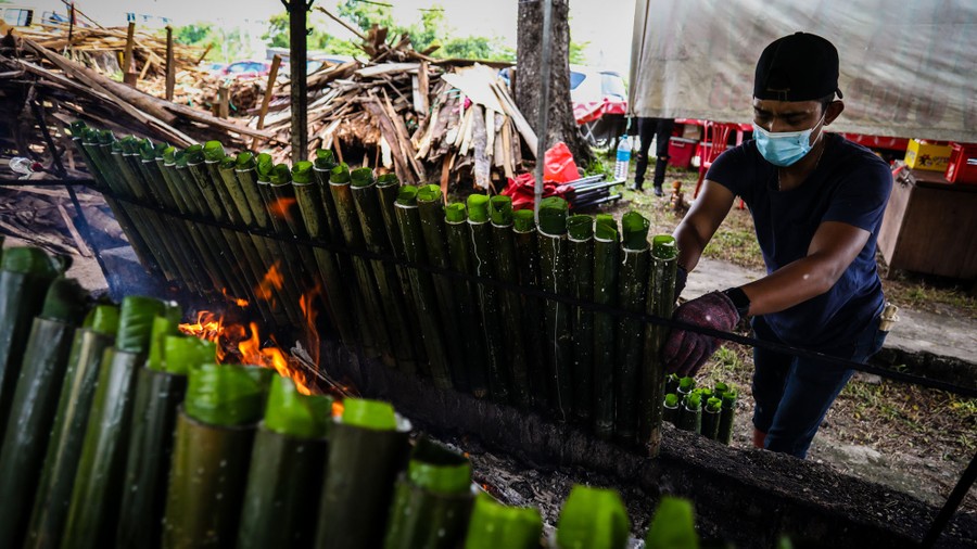 A man prepares traditional rice meals in bamboo tubes.