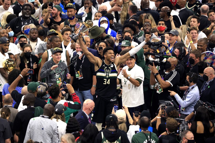 Giannis Antetokounmpo of the Milwaukee Bucks celebrates among dozens of fans and members of the press.
