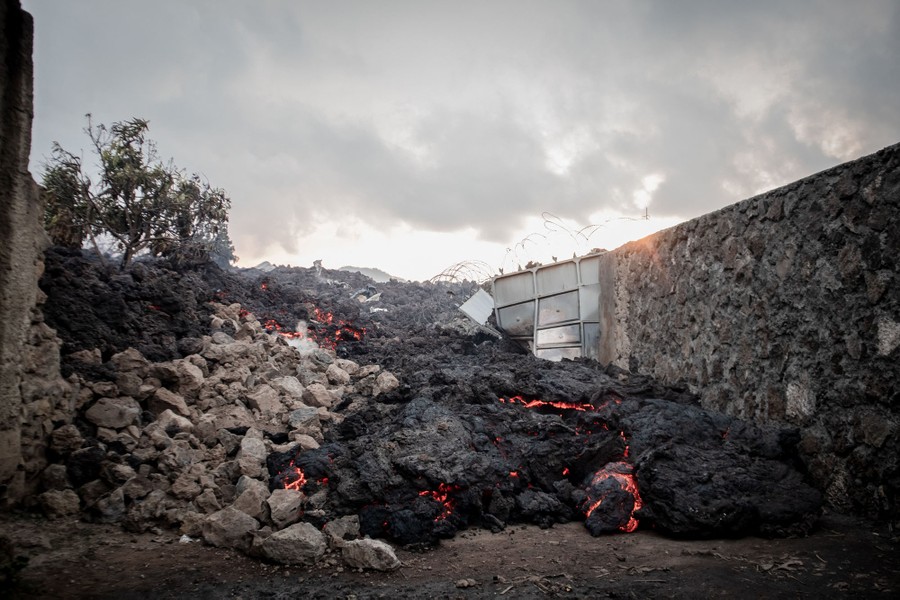 Lava flows past buildings.
