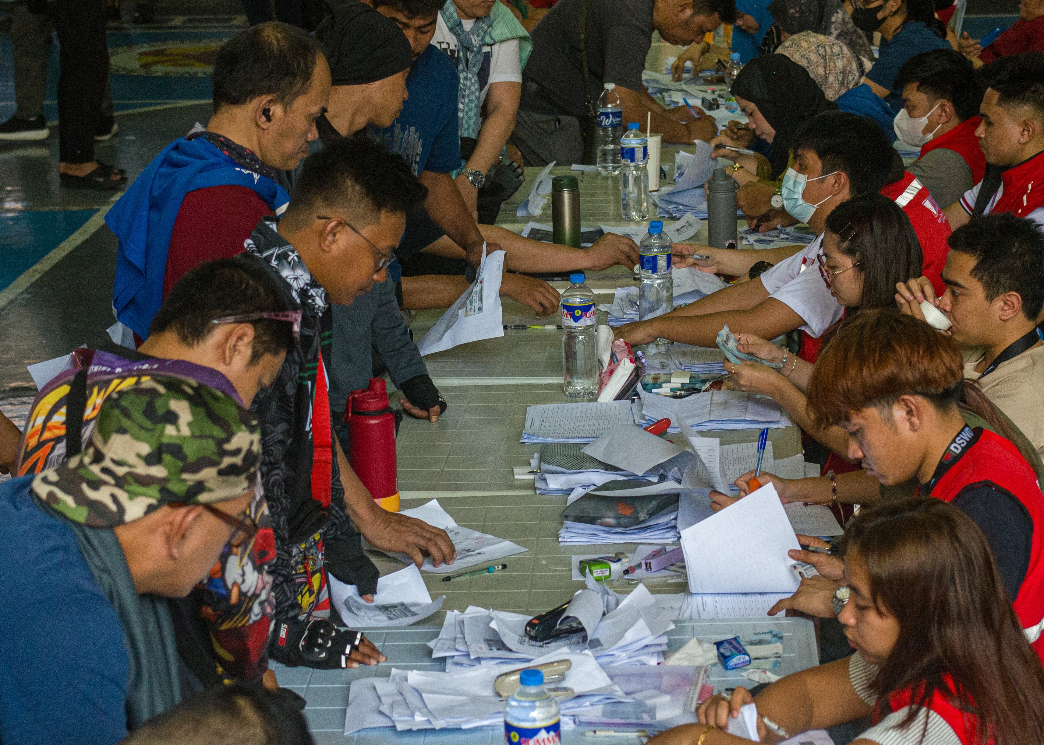 People line up at tables, signing papers and receiving money.