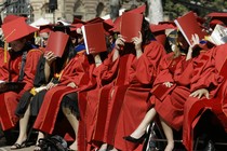 Women in graduation gowns covering their faces