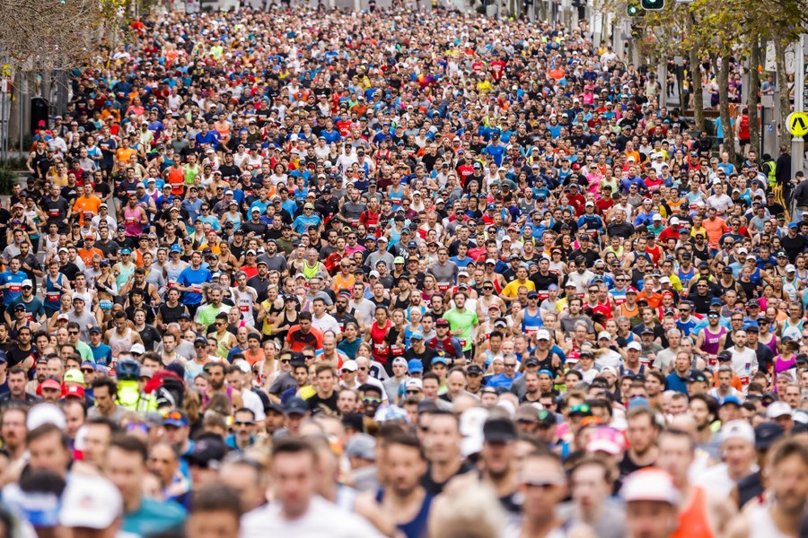 Thousands of athletes run together down a city street.