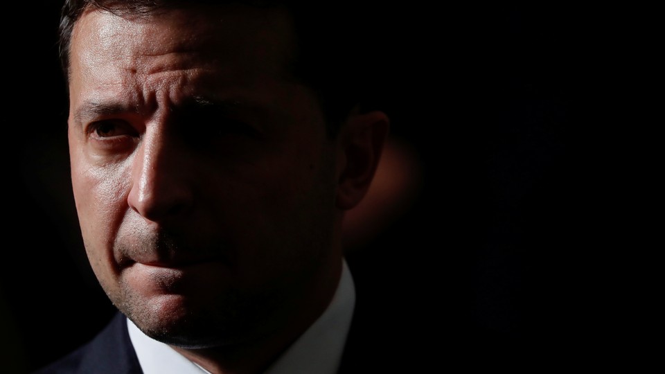 A close-up photo of Volodymyr Zelensky. Half of his face is covered in shadow.