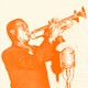 An orange-tinted photo of Louis Armstrong playing the trumpet in front of a microphone