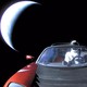 The dummy astronaut Starman, wearing a SpaceX space suit, in the driver's seat of a red Tesla Roadster in space as it speeds away from Earth