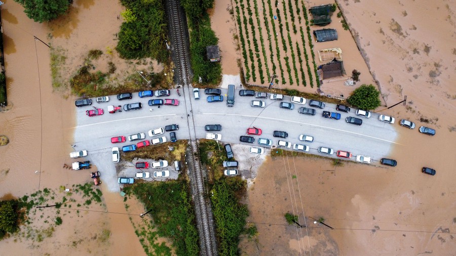 An aerial view of cars stuck on a raised bit of roadway, surrounded by floodwater