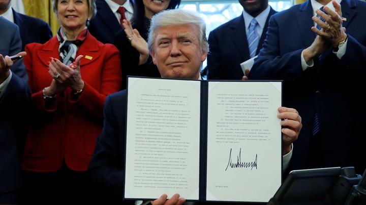 President Donald Trump holds a signed copy of an executive order