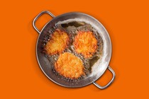 Three latkes frying in a pan