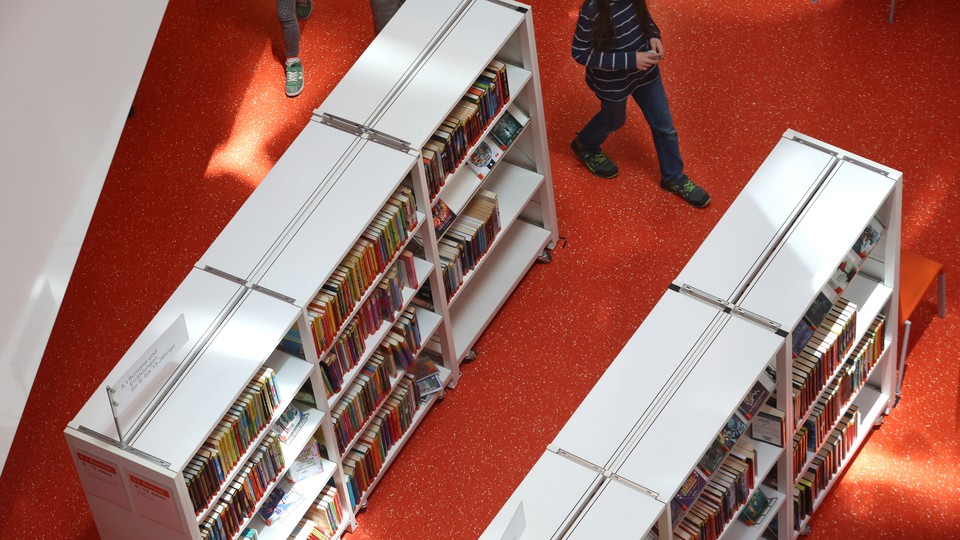 People walk between library shelves